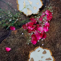 An aerial view of two mini gold Urli candles, styled with rose petals and baby's breath, showcasing their decorative potential.