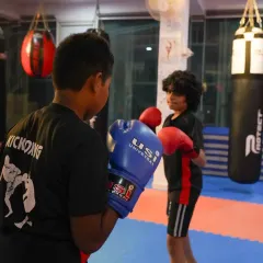 Focus and respect are taught from day one. Here, two of our young students face off in a controlled boxing drill, learning proper stance and guard under the watchful eye of a coach.
