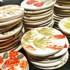 Stacks of my hand-painted floral coasters, ready to be packed up for gifting. Seeing them all together shows the incredible variety of colors and designs in the collection.