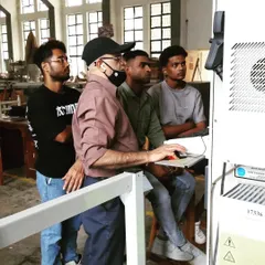 An instructor demonstrates the setup and operation of a CNC machine to a group of attentive students. This training covers how to translate a digital file into a machine-operated cutting process.