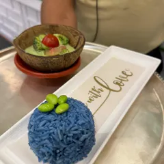 A close-up of our Thai Green Curry served with blue pea rice. The 'Made with Love' inscription on the plate reflects our philosophy of cooking from the heart.
