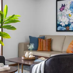 A cozy corner in the 'Pepper and Coffee' living room, where we used a mix of textures and colors, like the leather sofa and vibrant cushions, to create a warm and personal feel.