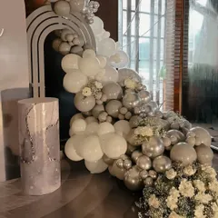 A close-up of the elegant monochrome balloon decor. The arrangement combines grey, white, and metallic silver balloons with sprigs of baby's breath for a soft, sophisticated look.