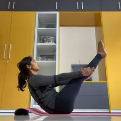 A student holds Ardha Navasana (Half Boat Pose) during an online session. This pose is excellent for toning the abdominal muscles and improving digestion.