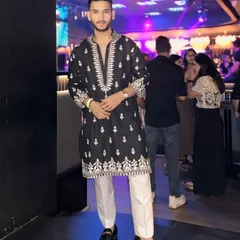 A stylish look for Dandiya Nights. This black kurta with detailed white embroidery is paired with classic white trousers and loafers for a look that blends tradition with modern styling.