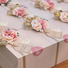 A detailed look at the handcrafted toppers on our return favour boxes. Each one includes a mix of faux flowers, pearls, and a gold ribbon, along with a personalized "Thank you for your love" tag.