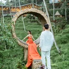 A dreamy, romantic shot from a pre-wedding session in Bali. The famous Bali swing, surrounded by lush greenery, creates a magical setting, and the flowing gown adds a touch of drama and elegance.