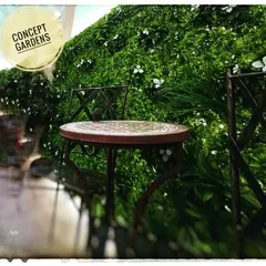 A simple cafe-style seating arrangement set against a backdrop of our artificial green wall with small white flowers. This creates a charming and maintenance-free outdoor cafe feel.