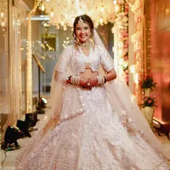 A joyful, full-length shot of the bride in her magnificent white lehenga. The makeup is designed to be bright and radiant, matching the celebratory and grand atmosphere of her wedding venue.