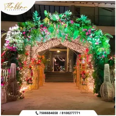 A lush and magical entrance canopy created with greenery, pink bougainvillea, and thousands of fairy lights. This design transforms a simple doorway into a grand and enchanting portal.