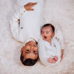 A creative overhead shot showing the two brothers side-by-side. The sleepy newborn's yawn next to his smiling big brother captures a real, unposed moment.