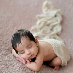 The perfect newborn curl. I use safe and gentle posing techniques to capture your baby sleeping peacefully on a soft, textured blanket.