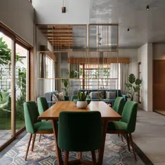 An open-concept dining area that showcases a mix of materials and patterns. The space is defined by traditional patterned floor tiles, which contrast with the modern dining set and a semi-transparent wooden partition that subtly divides the dining and living areas without obstructing the view.