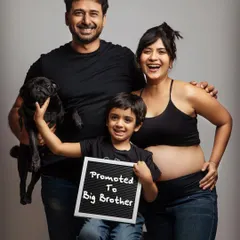 The whole family is excited! We absolutely love when siblings and even furry family members join the fun. This joyful family portrait with a "Promoted to Big Brother" sign is a perfect way to announce your growing family.