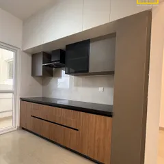 A clean and balanced parallel kitchen design. We used a mix of wood-finish and solid grey laminates with handleless drawers for a minimalist aesthetic that is easy to maintain.