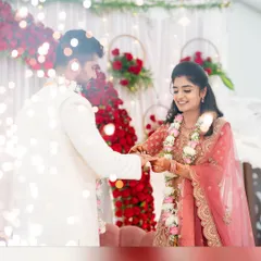 A beautiful moment from an engagement ceremony. The backdrop features a wall of red roses and hanging floral hoops, creating a romantic and photogenic setting.