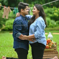 An expecting couple shares a loving look during their outdoor maternity shoot in a park. The natural green background adds to the fresh and candid feel of the portrait.