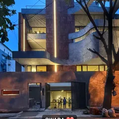 The 'SWARA' home at dusk, where integrated lighting highlights the curved forms and textured materials of the facade.