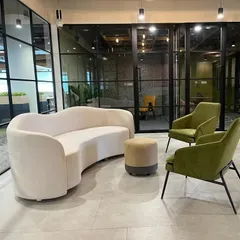 This is a lounge area in a corporate office I furnished. The curved sofa, modern armchairs, and pouffe were all custom-made to create a comfortable and stylish breakout space for employees.