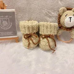 This unisex baby set includes cozy crochet booties and a matching lion rattle with a wooden teether ring. It's a perfect gift for a baby shower, designed to be both snuggly and playful.