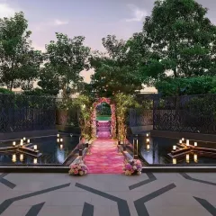 This magical entrance was created for a pastel-themed wedding. A floral arch and a pink carpeted walkway over a water body, surrounded by candles, provided a serene and romantic welcome for guests.