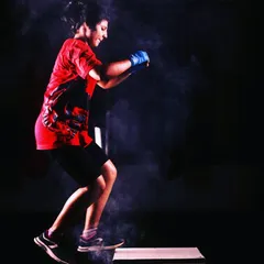 The same member demonstrates explosive power during a box jump. The chalk dust signifies the intensity and effort that defines our training sessions.