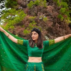 A vibrant outdoor portrait showcasing a beautiful green traditional outfit. The movement of the fabric adds a dynamic and joyful element to the photo.