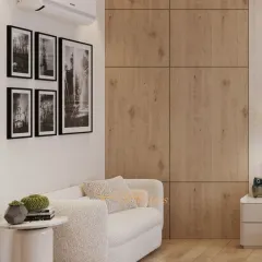 We created a cozy seating nook within the bedroom, featuring a comfortable bouclé sofa and a wood-paneled wall. The black and white gallery art adds a personal and sophisticated touch.
