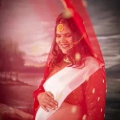 An artistic shot of a mom-to-be in a white and red traditional saree. The sheer red veil adds a layer of mystique and beauty to this culturally rich portrait.