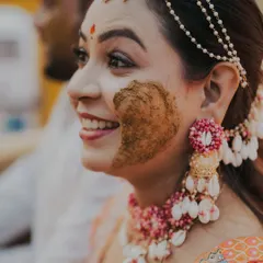 A playful smear of haldi and a radiant smile. I focus on capturing the genuine reactions and joyful moments of the turmeric ceremony.