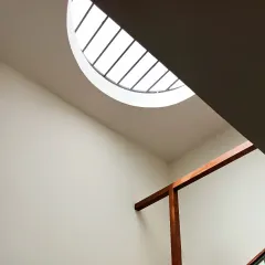 Beauty often lies in snippets and unique perspectives. This shot captures a gigantic circular skylight peeking down into a family room, with minimal walls and a rich veneer 'Sthambha' creating a beautiful composition of light, shadow, and texture.