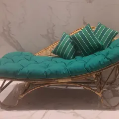 A full view of our rattan lounger with striped accent pillows. The fabric and cushion styles are fully customizable to your preference.