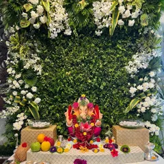A beautiful Ganpati decoration for the start of your celebrations, featuring a lush green wall and an abundance of white flowers.