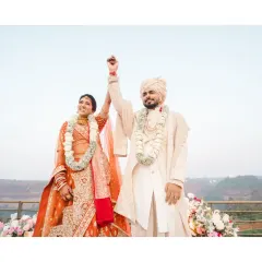 A triumphant moment for the couple after their varmala ceremony. This shot captures their pure joy and the beautiful, natural setting of their outdoor wedding.