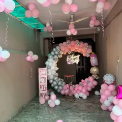 A beautiful "Welcome Baby" setup for a baby girl in a pink, white, and silver chrome color scheme. It features a circular balloon garland, a neon sign, and 'BABY' display boxes, all arranged to create a memorable welcome.