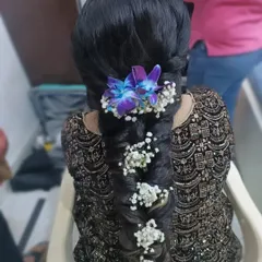 A stunning, thick braid adorned with fresh baby's breath and a vibrant purple orchid. This is a beautiful choice for a Mehendi or Haldi ceremony.