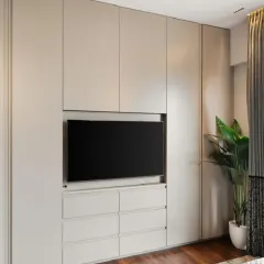 This image shows the complete integrated wall unit, combining a full-height wardrobe with a TV console and drawers. The neutral color and clean lines help the large storage unit blend into the wall, making the room feel spacious and organized.