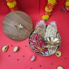 A sophisticated Diwali gift featuring a wooden-lid box. Inside, it holds dry fruits, a lotus-themed T-light holder, and an elephant diya, combining elegance with tradition.