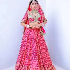 A full-length bridal portrait against a clean white studio background. This style puts all the focus on the stunning pink lehenga and the bride's complete look.