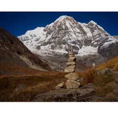 A moment of peace and balance. A trekker's cairn stands against the backdrop of the mighty Annapurna massif, a symbol of respect and mindfulness in the high mountains.