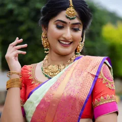 A radiant and happy client ready for her photoshoot. The makeup features a dewy finish with a strong highlight on the cheekbones and a bold lip, which pairs beautifully with the colorful silk saree.