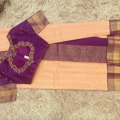 A beautiful pairing of a peach silk saree with a contrasting violet embroidered blouse. The rich jewel tone of the blouse makes the pastel saree pop.