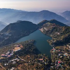 A wide aerial photograph of Naukuchiatal, capturing the lake nestled within the Himalayan foothills of Uttarakhand. This shot showcases my landscape photography service, perfect for highlighting the natural beauty of travel destinations or real estate properties from a breathtaking perspective.
