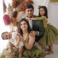A gorgeous family portrait with a warm, earthy feel. The coordinated olive green and cream outfits look stunning against the boho-style pampas grass backdrop.