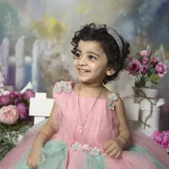 A beautiful portrait of a toddler in a pink and green tulle dress, set against a whimsical, painted garden backdrop.