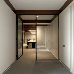 The entrance to a main conference room, framed by black metal and glass. This design choice creates a visual connection to the corridor, making the entire floor feel more open and accessible.