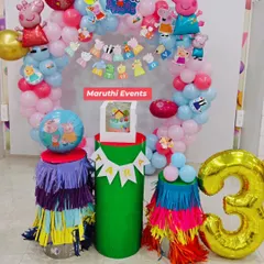 A cheerful Peppa Pig party for Tara's 3rd birthday. This decor features a circular balloon arch, character cutouts, themed plinths with colorful tassels, and a large golden number '3' balloon.