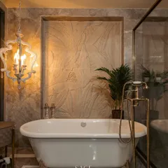 I believe a master bathroom should be a private retreat. Here, a classic clawfoot tub is set against a backdrop of textured stone and marble, with ornate brass fixtures and a statement chandelier adding a layer of opulence. It is a space designed for indulgence and tranquility.