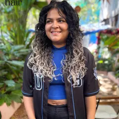 The happy client showing off her new silver ombre curls. Our CGM-friendly approach ensures that even after a bleach and tone process, the curls remain healthy and defined.