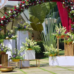 An elegant floral photo booth at a resort wedding. The red arch and arrangements of white and purple flowers create a beautiful contrast with the green lawns.